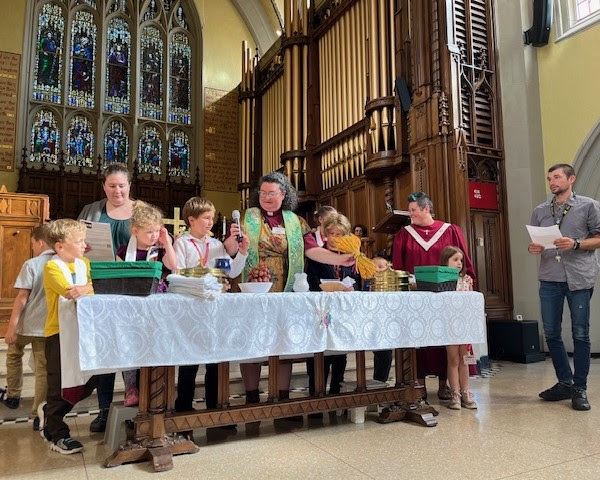 A pastor at a communion table, surrounded by children and their parents